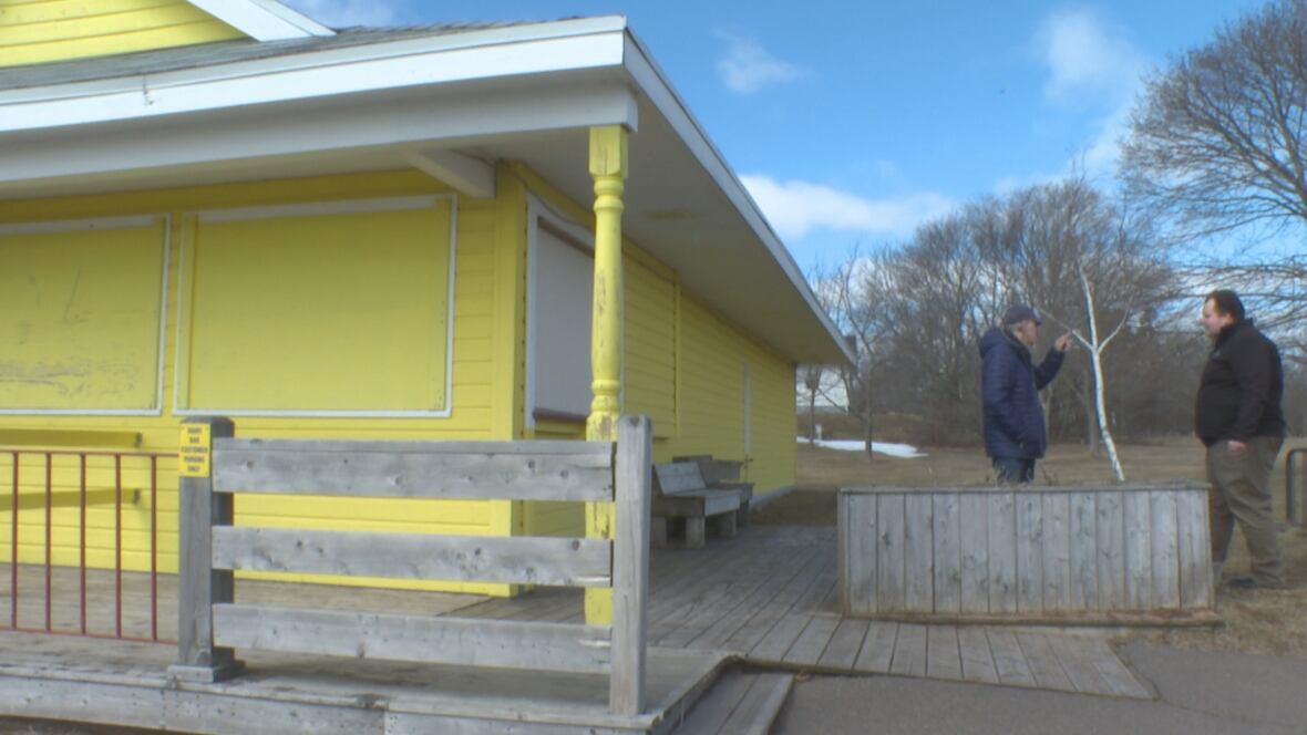 Two men talk beside closed dairy bar.