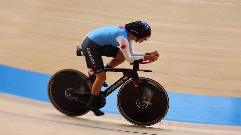 A female Paralympic track cyclist races around a velodrome.