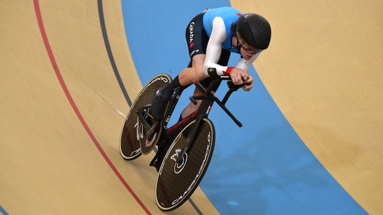 A male Para track cyclist races inside a velodrome.