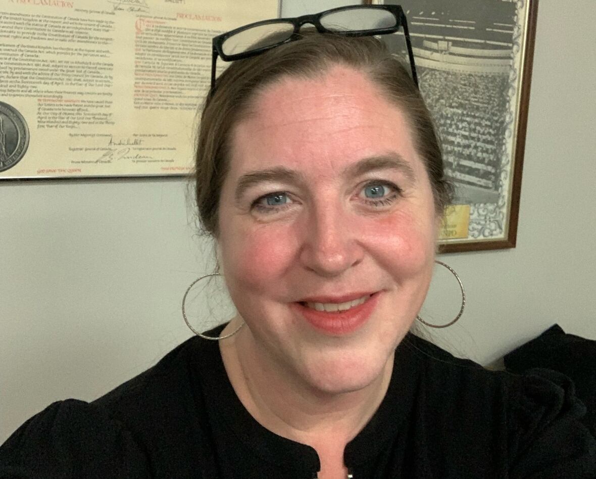 A woman smiling and taking a selfie.