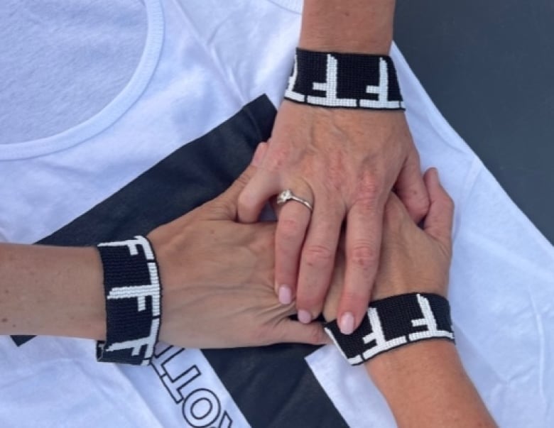 Three hands stacked on top of each other. All of them have a black bracelet with white Full Throttle logos.