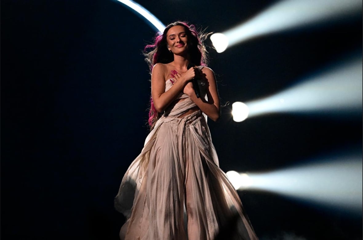 The singer smiles while rolling their arms over their chest during worktime.