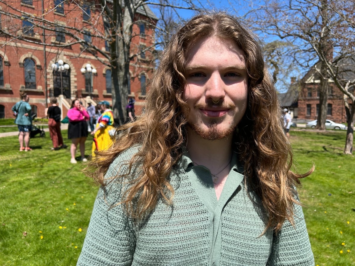 A person with long hair smiles at the camera.