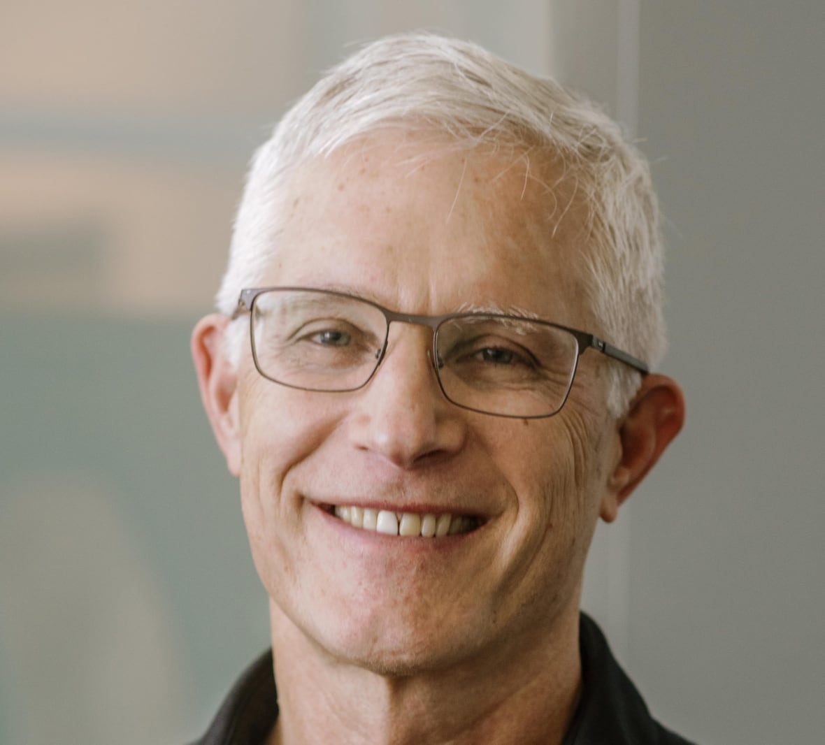 Smiling man with white hair and glasses