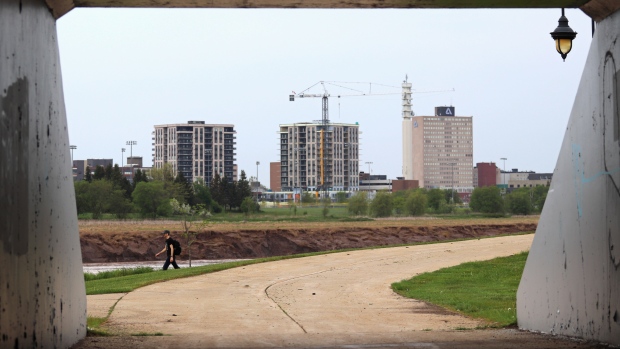 Southeast N.B.'s booming population leads Canada; A man walks along a trail in Riverview with the Moncton skyline in the background on May 23, 2024\.
