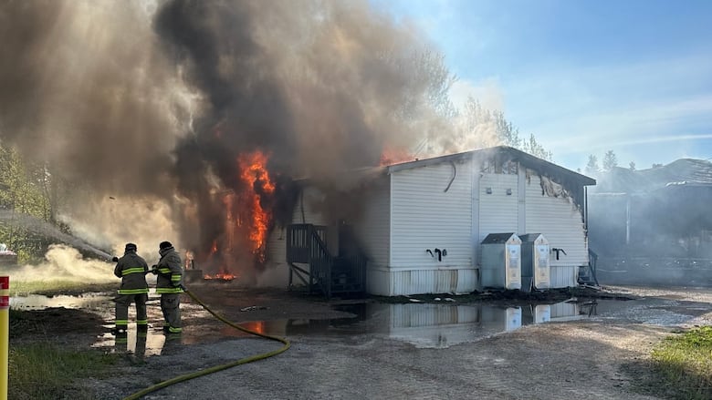 firefighters with hose pouring water on fire