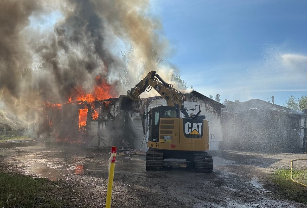 backhoe takes down burning building