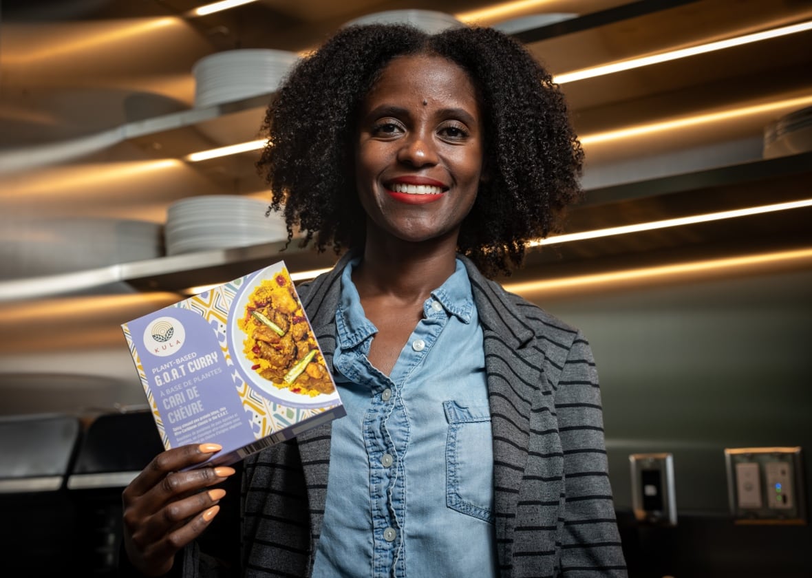 A woman smiles while holding a purple package of plant-based curry.