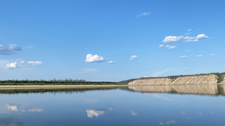 Looking out at a still river on a clear sunny day, from a boat.