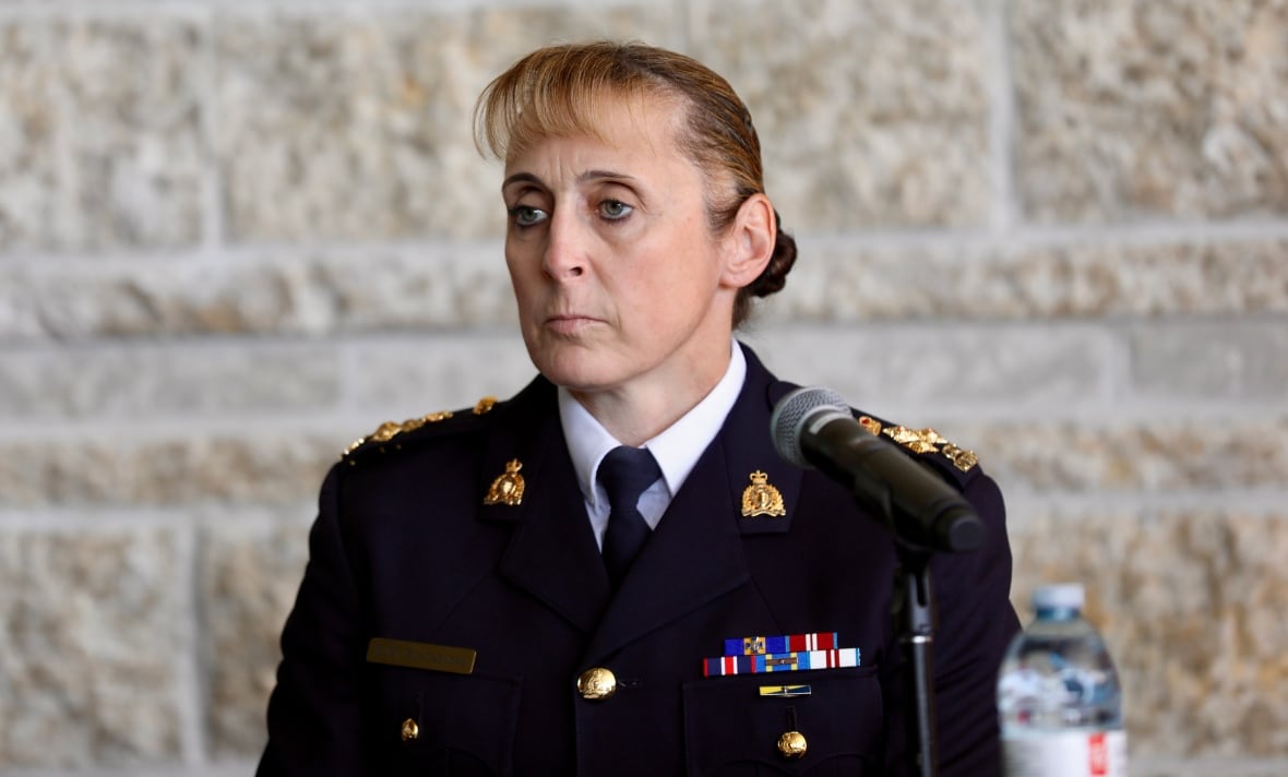 A woman in an RCMP uniform with many medals sits in front of a microphone.