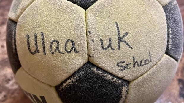 A weathered felt soccer ball sits on a counter. The ball reads 'Ullajuk School' in what appears to be black marker.