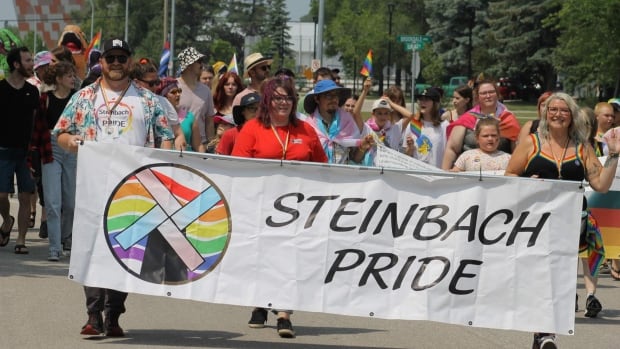 People holding a sign that says Steinbach Pride