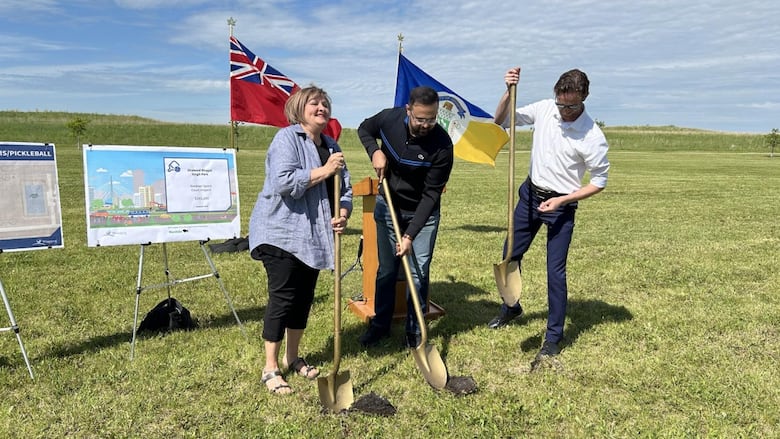 Three people hold shovles for a sod-turning.