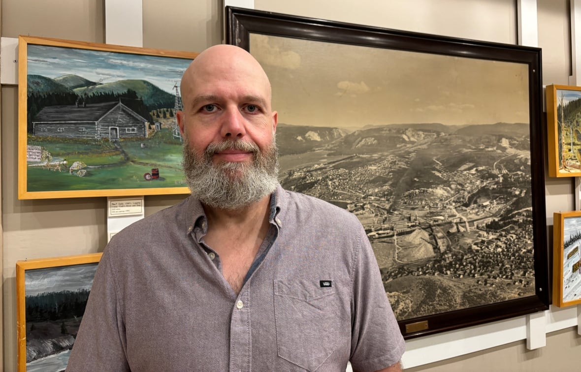 A man standing next to pictures in a museum.