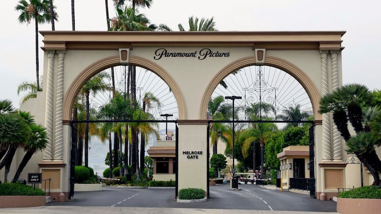 A large, cream-coloured gate is surrounded by palm trees.
