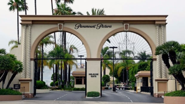 The main gate to Paramount Studios is seen on Melrose Avenue, July 8, 2015, in Los Angeles. Entertainment giant Paramount will merge with production company Skydance, closing out a decades long run by the Redstone family in Hollywood and injecting desperately needed cash into a legacy studio that has struggled to adapt to a shifting entertainment landscape. A large, cream-coloured gate is surrounded by palm trees.