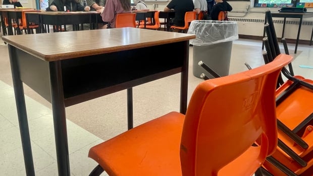 P.E.I. school officials don't track the overall number of students on reduced schedules, or the reasons for it. An empty desk is seen with students sitting in other desks in the distance.