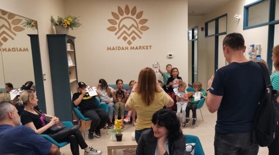 A crowd of 20 people stand together in a small room, smiling and talking.