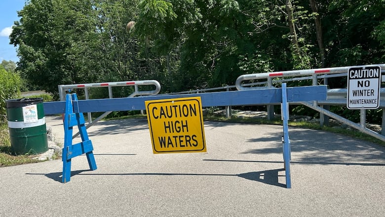 Blue barrier at a trail with a sign that says "caution high waters." 