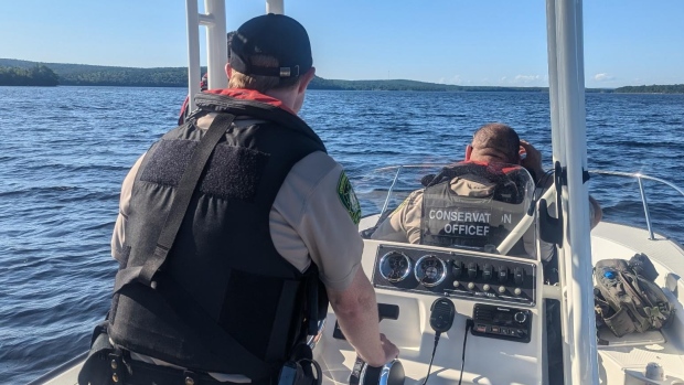 N.S. lake patrol results in 1 arrest, 4 alcohol-related tickets, 115 warnings; Two officers with their backs to the camera ride in a boat on a lake\. 