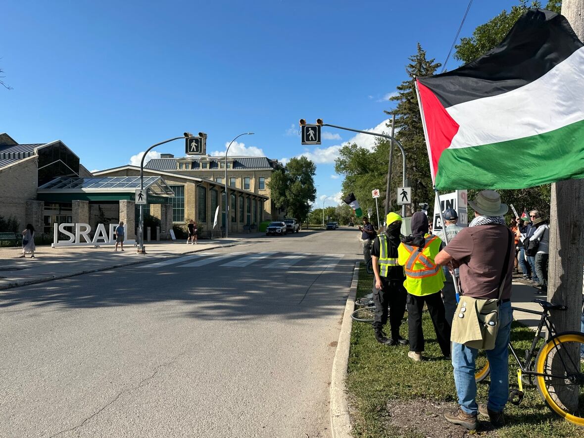 Protestors wave Palestinian flags and hold signs outside.