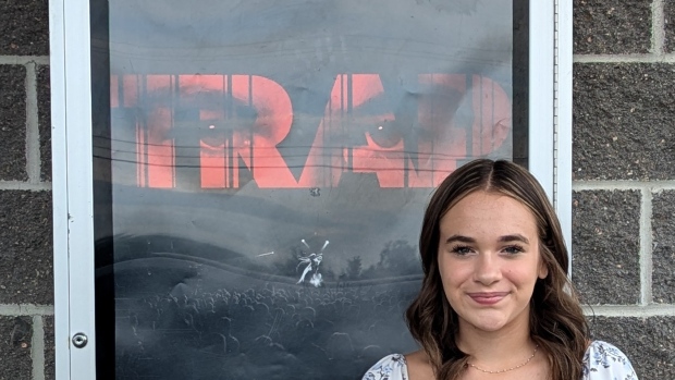13-year-old Woodstock girl onscreen in U.S. thriller; Juliet stands in front of Trap movie poster, a film she appears in as a singer in the crowd\. 