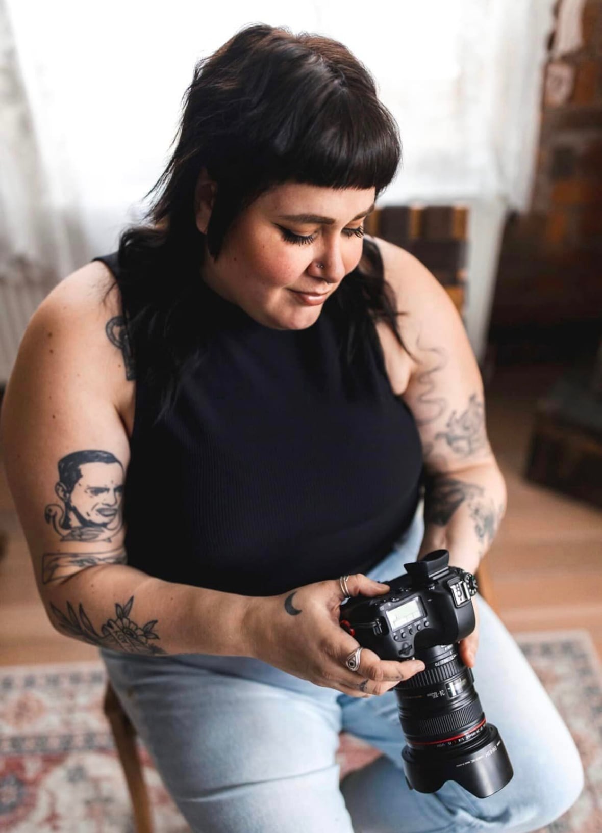 A woman looks down at her camera. 