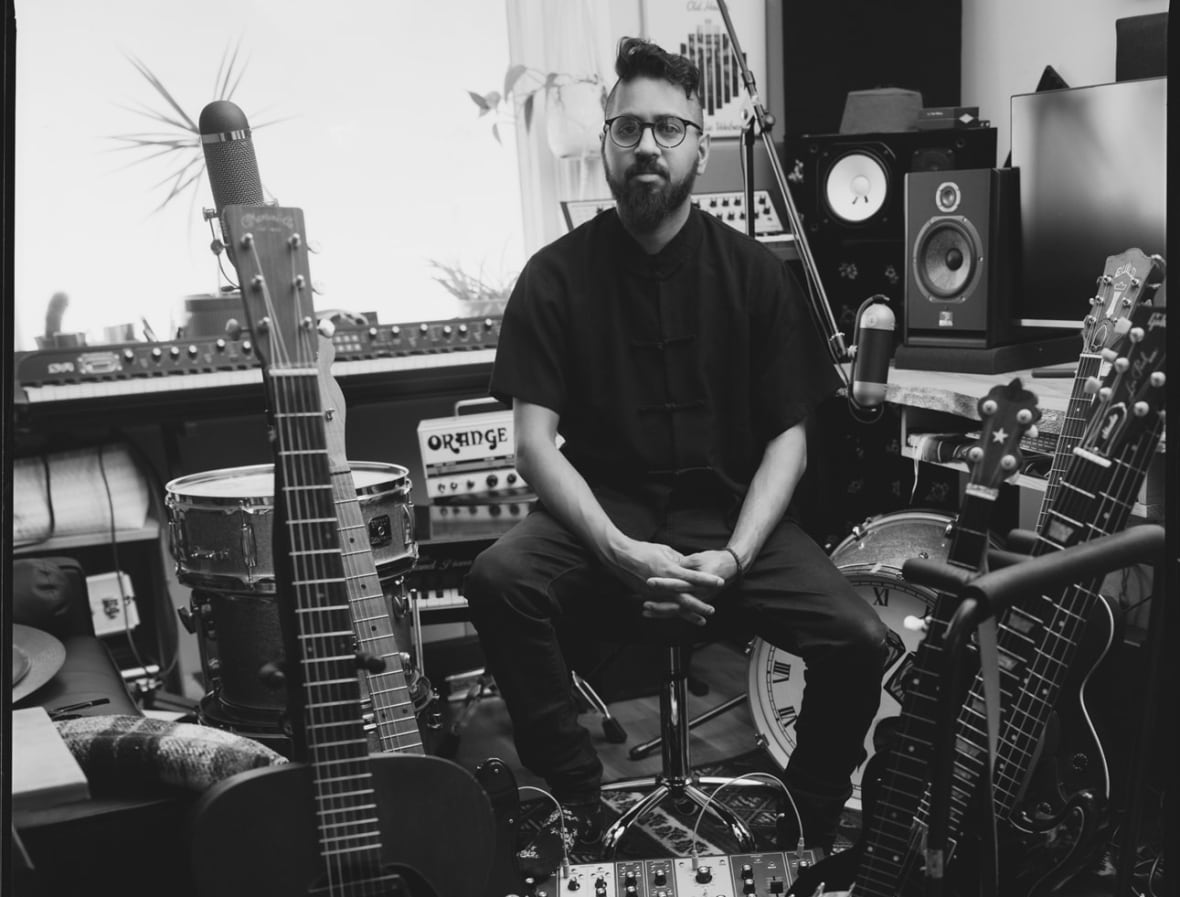 A black and white photo of a man sitting among instruments. 