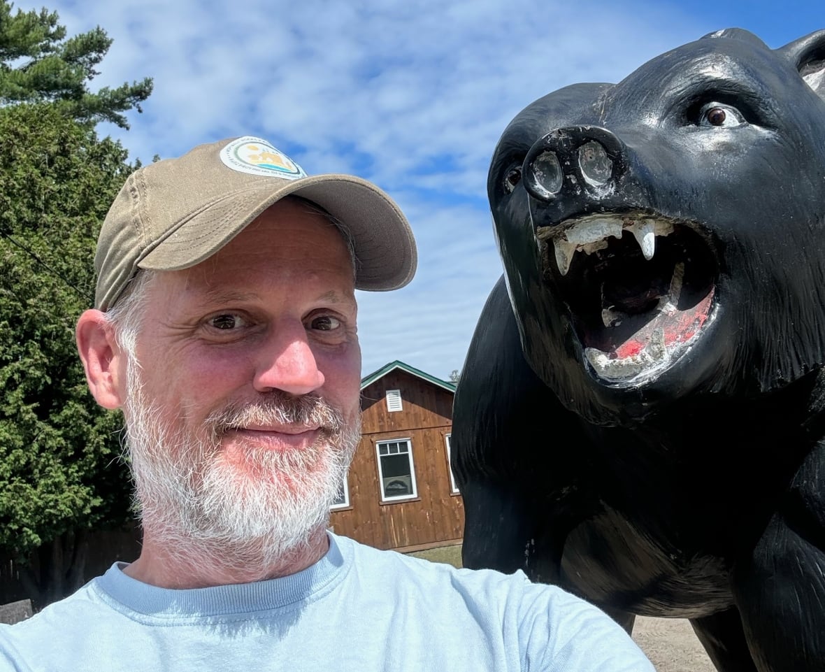 A man takes a selfie with a black cow statue.