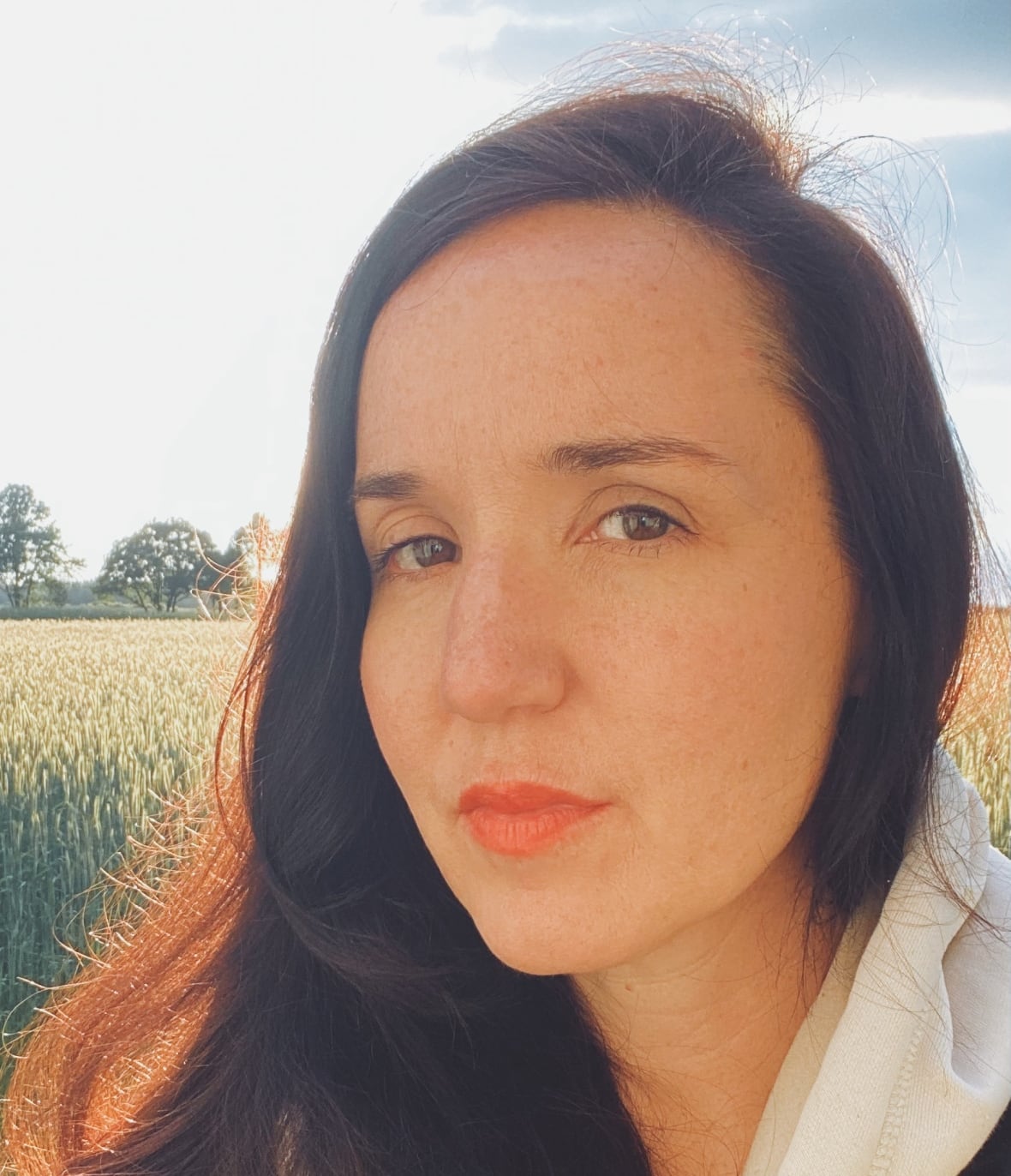 A woman smiles at the camera outdoors. 