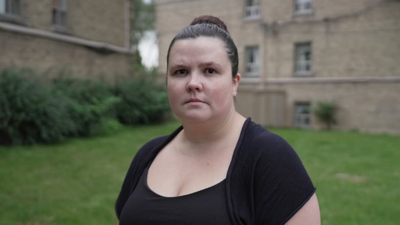 Woman standing in front of apartment buildings.