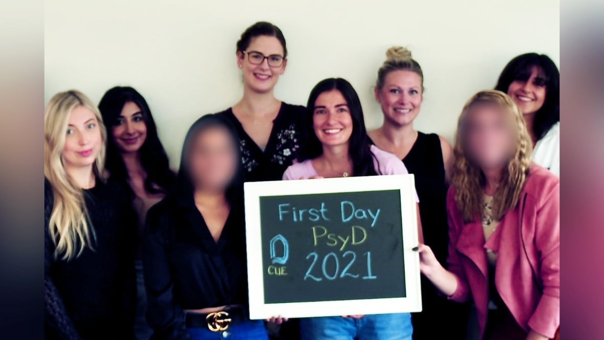 Eight people, two with faces blurred, stand while one holds a sign that says "First Day PsyD 2021."