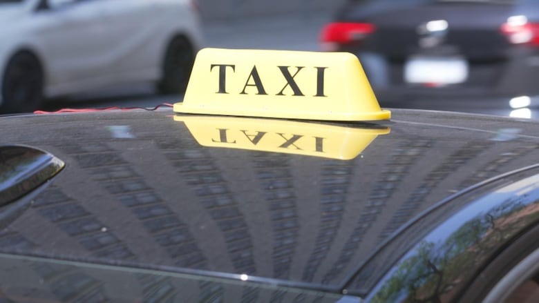 A yellow taxi sign sitting on top of a car.