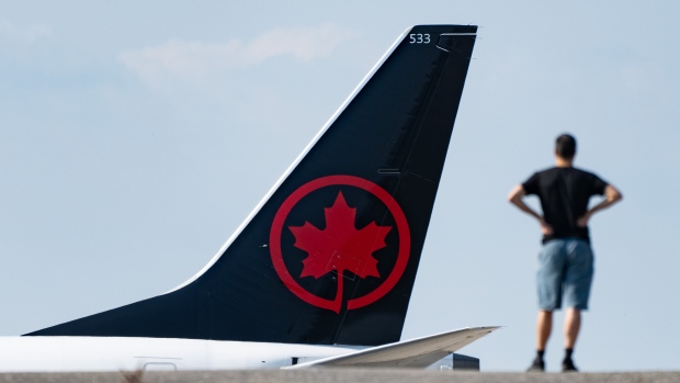 Air Canada says strike averted after tentative deal with pilots; A person watches as an Air Canada plane lands at Montreal-Pierre Elliott Trudeau International Airport in Montreal, Friday, Sept\. 13, 2024\.  