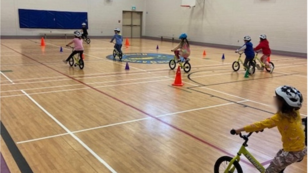 More physical education coming for K-8 schools this year; Elementary students sitting on bikes in a gymnasium with their backs to the camera\.