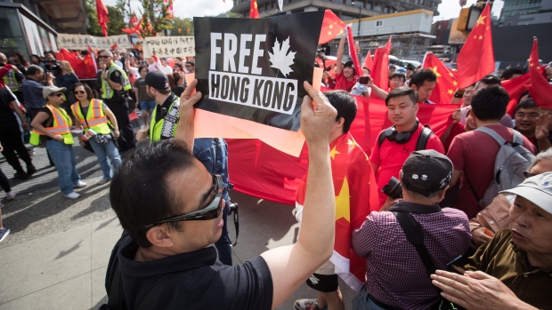 Chinese students in Canada say they've been targeted by Beijing's campaign of fear; A Hong Kong anti-extradition bill protester holds up a sign in front of pro-China counter-protesters during opposing rallies in Vancouver on Saturday August 17, 2019\.
