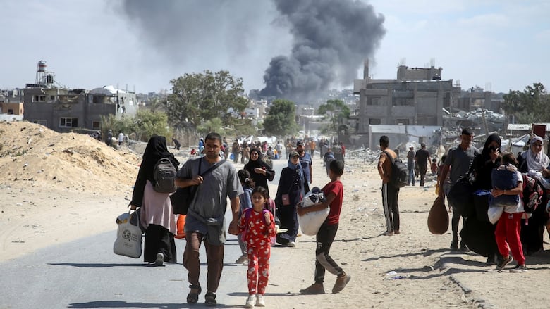 Smoke rises following an Israeli strike as displaced Palestinians make their way to flee areas in the eastern part of Khan Younis in the Gaza Strip.