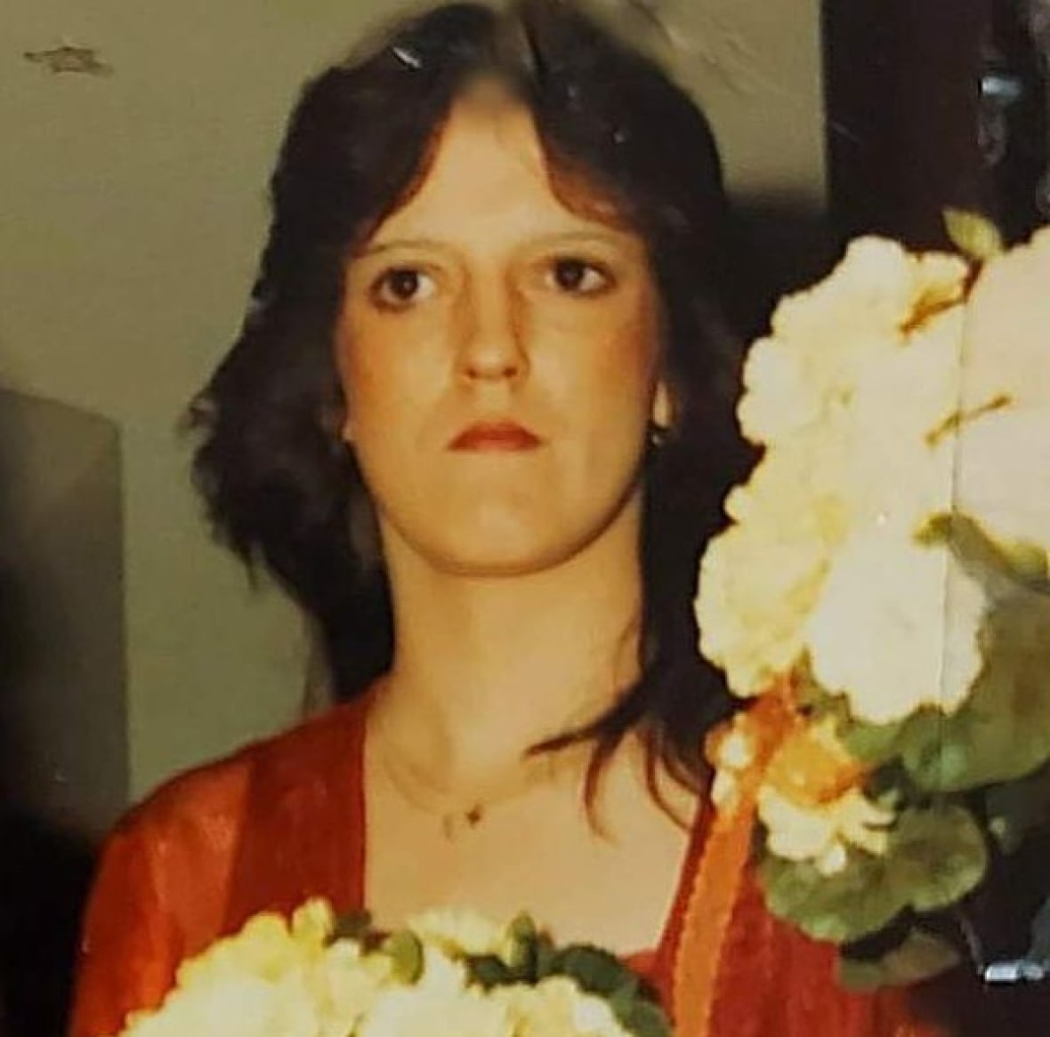 Woman in red robe holding flowers.