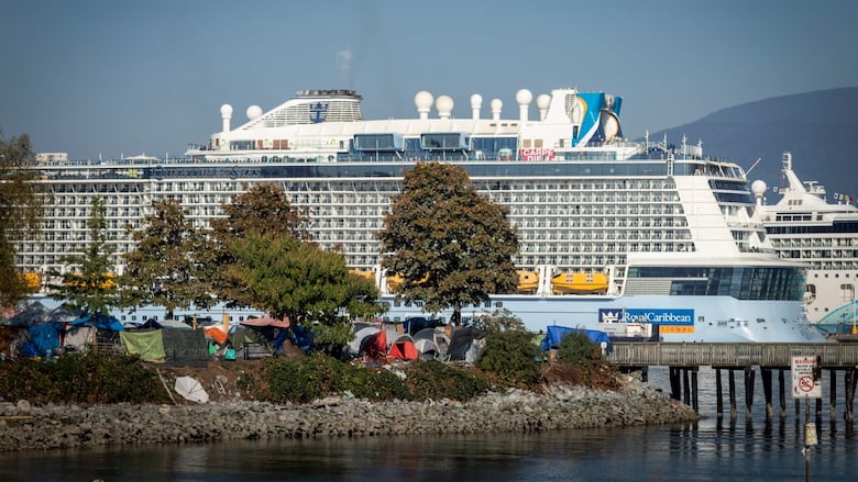 A series of makeshift tents are pictured beneath a looming cruise ship.