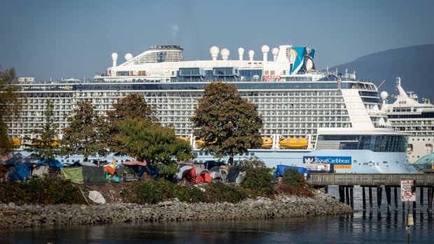 A series of makeshift tents are pictured beneath a looming cruise ship.