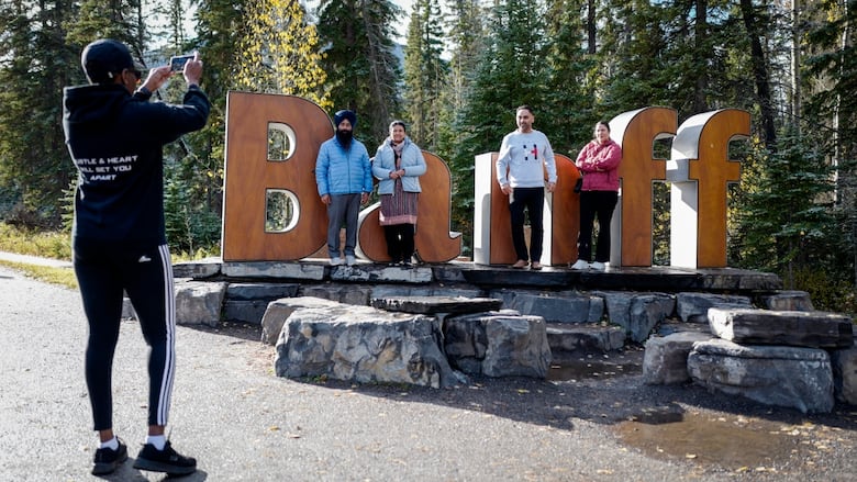 Tourists pose for pictures on a sign in Banff.