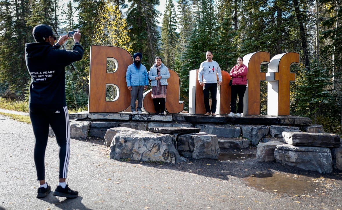 Tourists pose for pictures on a sign in Banff.