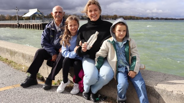 Makenzie Van Eyk holds the message in a bottle she threw into Lake St. Clair 26 years ago. She's sitting with her teacher from that time and her two kids. They're in the area where she sent the plastic bottle into the water and where it was found. 