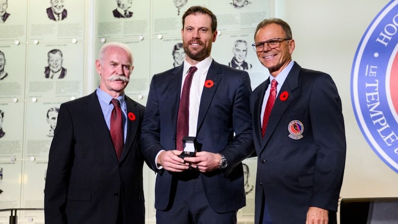 Three men in suits are seen posing for a picture.