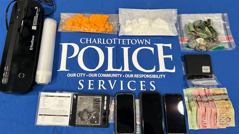 Drugs, cash, cell phones and other drug paraphernalia laid out on a table.