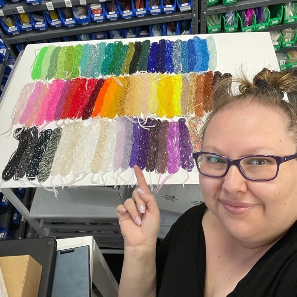 Una mujer está cerca de mostrar las coloridas cuentas sentadas en una mesa detrás de ella.
