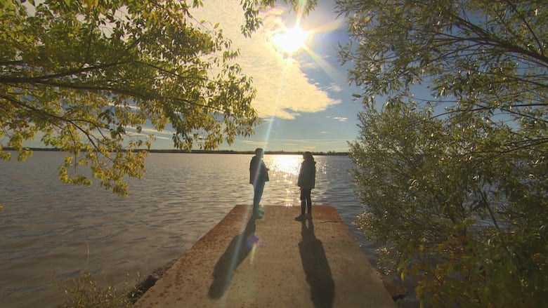 The silhouettes of people standing in the sunshine on a dock on Lac du Bonnet, Manitoba.