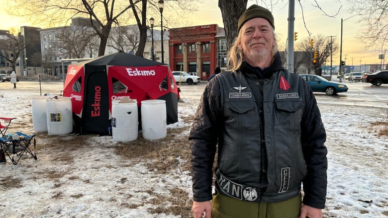 Man is standing besides a fishing tent.