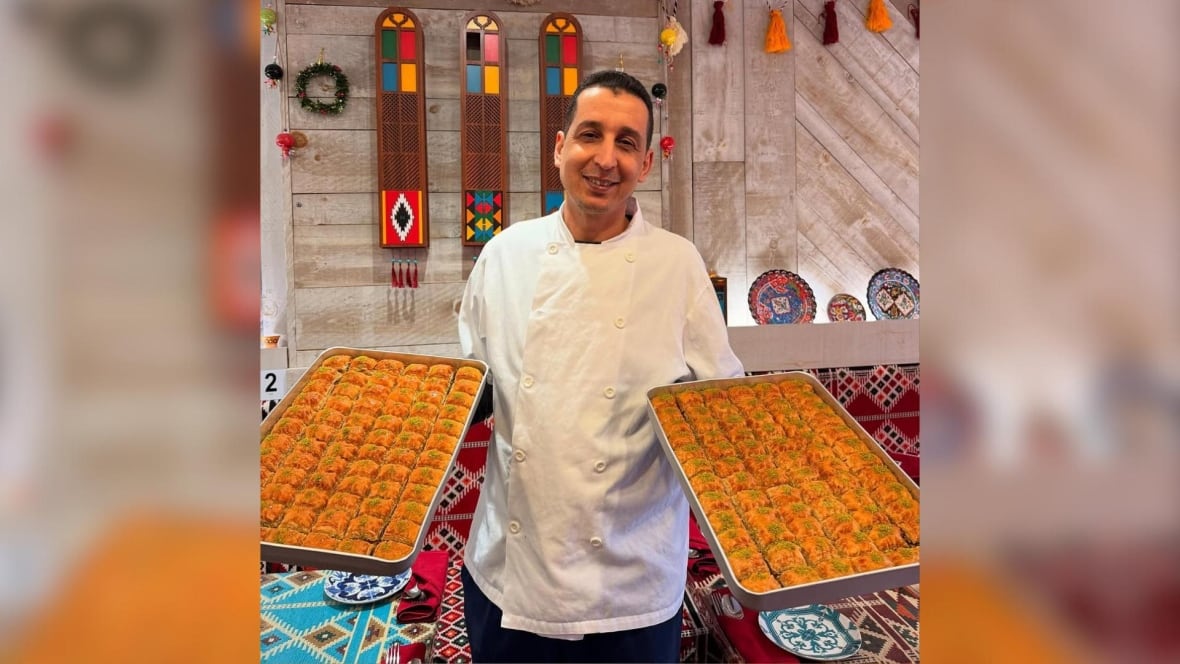 A person in a chef carries two pages filled with pastries.