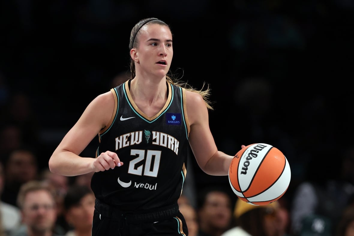 A women's basketball player wearing number 20 dribbles the ball with her right hand during a game.